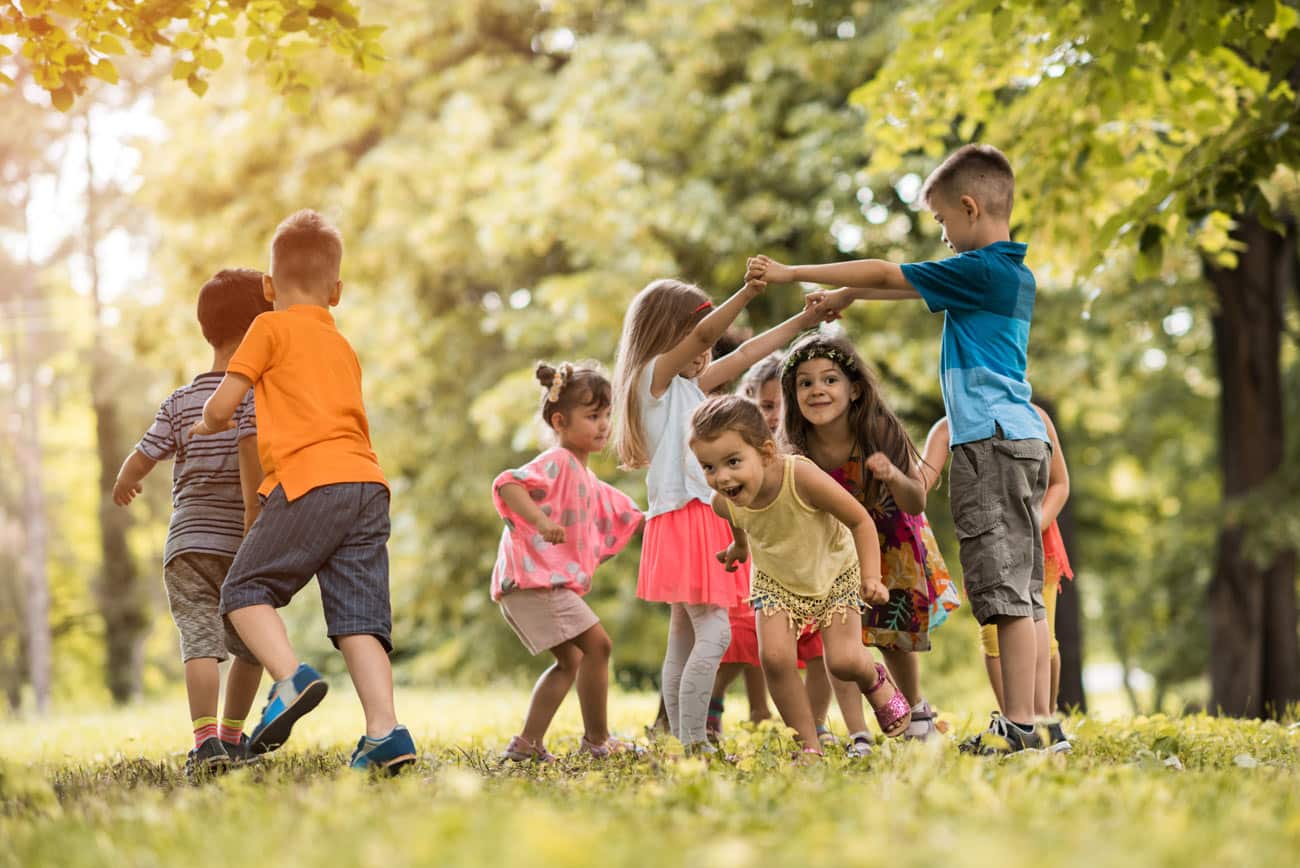 Kinder, die vergnügt auf einer Wiese spielen